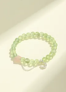 Detailed macro view of prehnite beaded bracelet with rose quartz star and moon charm.