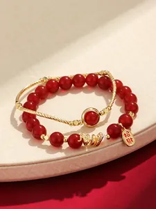 Close-up of red agate beaded bracelet featuring a gold dragon charm and pearl accent