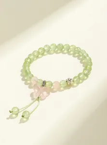 Detailed view of prehnite and rose quartz beaded bracelet with pink butterfly charm