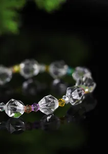 Detalle macro de una pulsera de cristal transparente facetado con cuentas de colores.