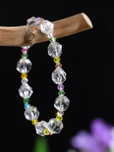 Primer plano detallado de una pulsera de cristal tallado con cuentas de colores en rama
