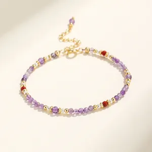Primer plano de una elegante pulsera de amatista púrpura y cuentas doradas sobre fondo claro