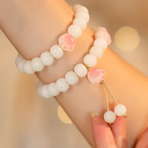 White jade Bodhi seed bracelet set with pink cat paw charms and soft warm lighting