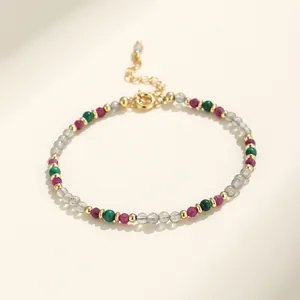 Detalle macro de una delicada pulsera de cuentas multicolor con labradorita, malaquita y rubí