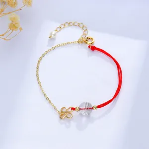 Detailansicht eines handgemachten roten Seilarmbands mit goldenem Glücksknoten und Kristall