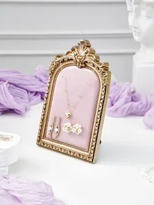 Detailed view of vintage gold resin jewelry display stand with pink velvet for necklace earrings.