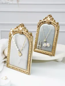 Vintage gold resin jewelry display stand detail, arched frame for necklace and earrings.