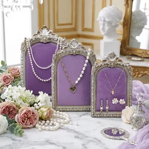 Vintage ornate silver jewelry display stands with purple velvet inserts on marble surface
