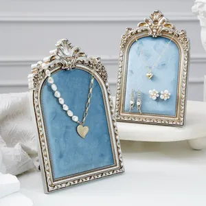 Detail view of vintage ornate jewelry display stands with blue velvet and heart necklaces.
