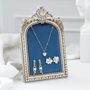 Vintage ornate jewelry display frame with blue velvet backing for elegant necklaces