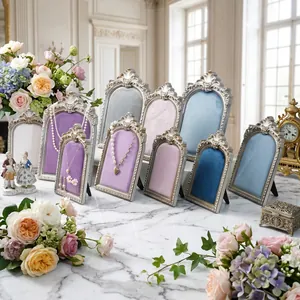 Vintage velvet jewelry display stand set with ornate silver carved frames on marble.