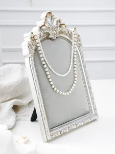 Detailed close-up of vintage resin photo frame jewelry display stand with elegant silver carved border.