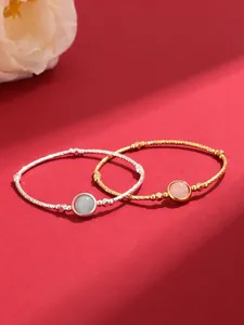 Detailed macro view of gold and silver twisted bangles with pink and blue stones