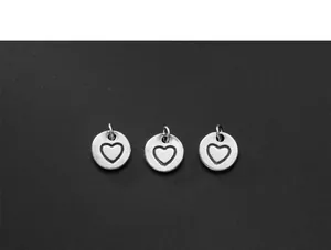 Close-up detail of three antique silver heart circle charm pendants for DIY jewelry making.