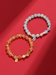 Detail view of freshwater pearl and aquamarine beaded bracelets with wealth charms