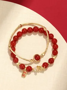 Detailed shot of red agate beaded bracelet set with gold dragon charm and blessing tag
