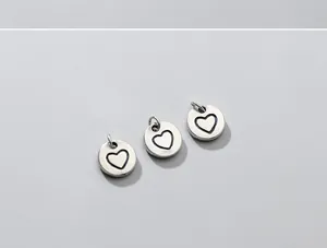 Detail shot of three S925 sterling silver heart round charms, vintage DIY jewelry making pieces.