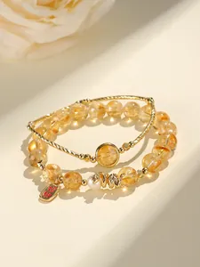 Close-up of yellow crystal beaded bracelet with snake charm and gold bangle set
