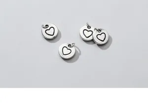 Detailed view of small sterling silver heart charms, perfect for DIY bracelet and necklace.