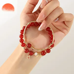 Red agate and freshwater pearl beaded bracelet with lucky gold charm on woman's wrist