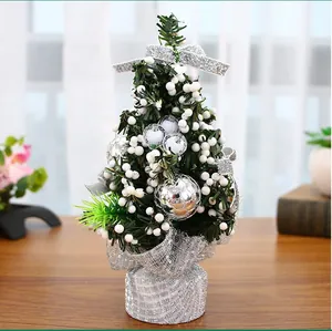 Nahaufnahme eines 20 cm kleinen Weihnachtsbaums mit silbernen Kugeln und weißen Beeren