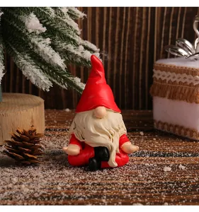Macro detail of a Christmas gnome figurine in a meditation yoga pose on snow