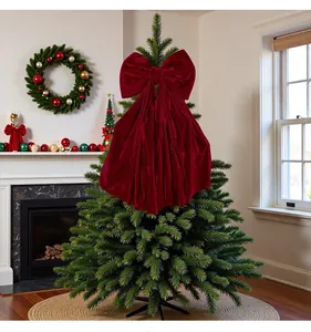 Große burgunderrote Samt-Weihnachtsschleife als Baumschmuck in gemütlichem Wohnzimmer.