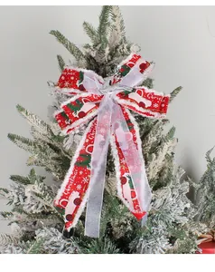 Rote Weihnachtsschleife mit weißem Truck-Muster auf einem festlichen verschneiten Baum.