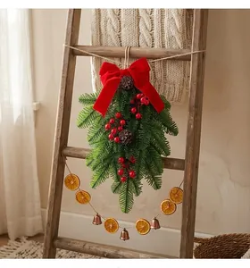 Close-up of a festive Christmas pine swag with a red velvet bow and berries on a wooden ladder.