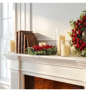 Coronas de anillos de velas de eucalipto y bayas rojas en una chimenea blanca decorada