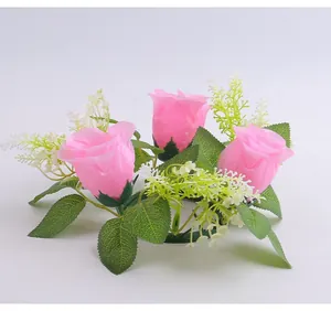 Vista detallada del anillo de vela de rosa artificial rosa con hojas verdes y flores blancas