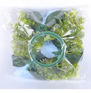 Artificial flower candle holder wreath in clear plastic packaging for festive table decor