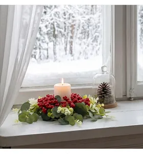 Detalle de una corona de velas de eucalipto de Navidad con bayas en un alféizar nevado