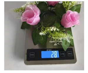 Medición de peso de una corona de rosas artificiales rosas que marca 28g en báscula