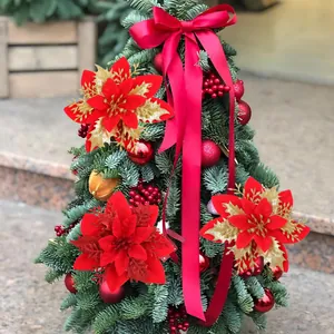 Fleurs de poinsettia rouges et dorées décoratives et ruban sur un mini sapin de Noël