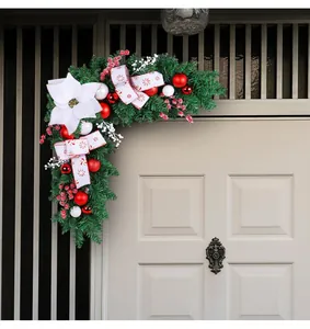 Festive Christmas door corner swag with red baubles and white poinsettia detail.