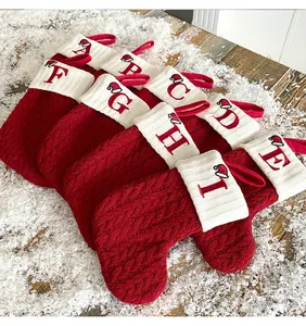 Primer plano de calcetines de Navidad de punto trenzado rojo con puños blancos bordados con letras