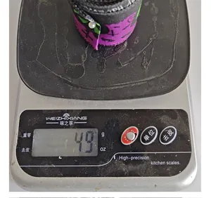Vista detallada que muestra el peso de 49 g de la cinta decorativa morada de Halloween en báscula