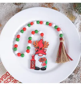 Detailed view of a Christmas gnome wooden bead garland with tassel on a white plate.
