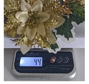 Close-up of golden Christmas glitter flower ornament weighing 44g on digital scale