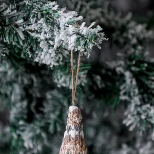 Handmade knitted Christmas gnome plush ornament hanging on snow-dusted tree branch
