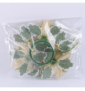 Christmas candle holder wreath with gold petals and green leaves in plastic packaging