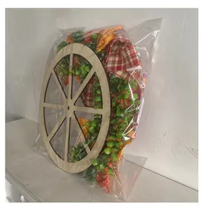 Side detail view of Thanksgiving pumpkin wagon wheel wreath in plastic packaging