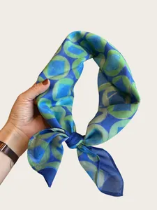 Detail view showing the soft texture and geometric print of the blue silk neckerchief scarf