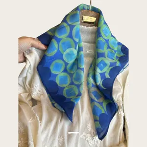 Detailed view of women's blue and green geometric print silk scarf on lace outfit