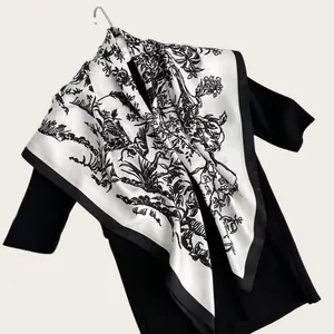 Close-up of a sophisticated ink-wash floral silk scarf draped on a black dress.
