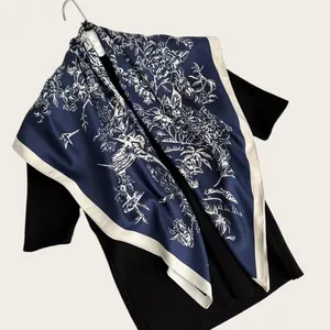 Detail shot of navy blue silk scarf with white ink-painted bird and flower patterns