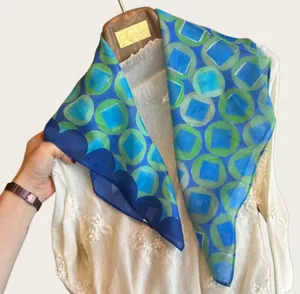 Detail of lightweight blue geometric print scarf with sheer texture and vibrant patterns