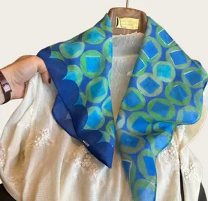 Detailed view of lightweight blue silk scarf with green geometric circle patterns