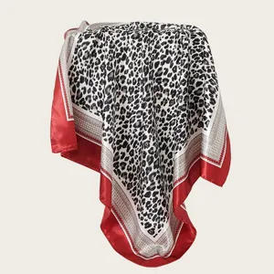 Detail view of a 90cm leopard print satin square scarf featuring red and white borders